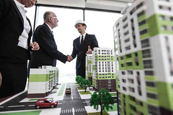 Business people standing near houses models